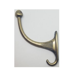 May include: A gold-toned metal hook with a decorative, fluted design. The hook has a rounded top and a curved arm.