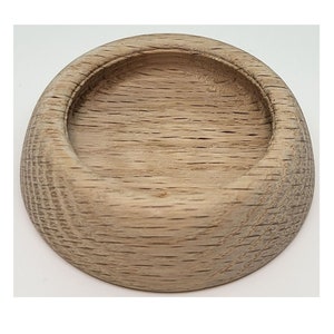 May include: A round wooden coaster with a smooth, slightly concave top surface. The coaster is made of light brown wood with a natural grain pattern.