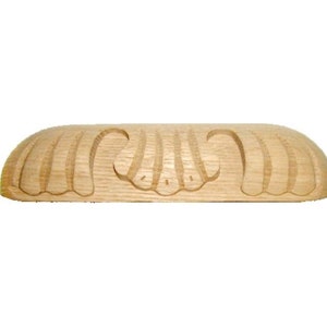 May include: A wooden furniture carving with a scalloped edge and a raised, textured design.