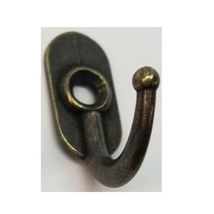 May include: A single antique bronze hook with a rounded top and a flat back plate. The hook is designed for hanging items on a wall.