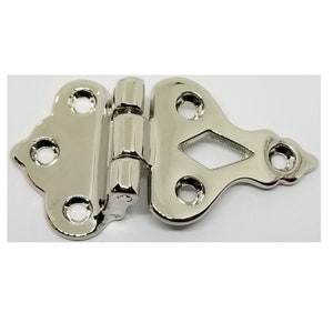 May include: A silver-toned, decorative hinge with a diamond-shaped cutout. The hinge has four holes on each side for attaching to a surface.