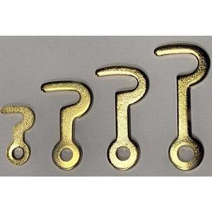 May include: Four gold-colored metal hooks of varying sizes. The hooks are all in the shape of a question mark with a circular loop at the bottom.