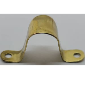 May include: A gold metal pipe clamp with two holes on each side. The clamp is designed to hold a pipe in place.