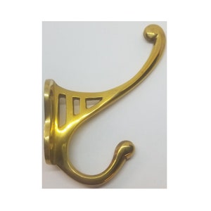 May include: A gold-toned metal hook with an ornate design. The hook has a curved shape and a decorative base.