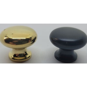 May include: Two cabinet knobs, one gold and one black. The knobs are round with a small base.