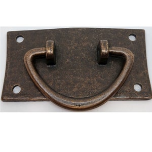 May include: A rectangular, antique bronze drawer pull with a curved handle. The pull has a distressed finish and four screw holes for mounting. This hardware is suitable for cabinets, drawers, and other furniture.