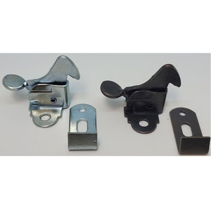 May include: Two cabinet door catches, one in silver and one in black. Each catch has a lever handle and a mounting plate.