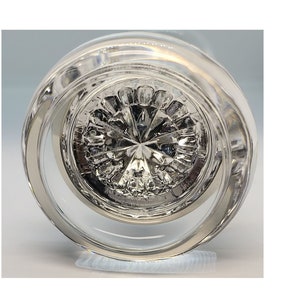 May include: The bottom of a clear glass bottle with a decorative, star-shaped design.