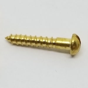 May include: Three gold-colored screws with round heads. The screws have a threaded shaft and a flat head.