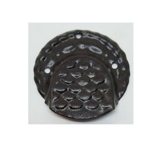 May include: A black metal cabinet door pull with a textured, scaly design. The pull has two holes for mounting.