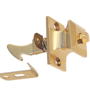 May include: A gold-toned door latch with a spring-loaded mechanism. The latch has a rectangular base and a lever that extends out to the side. The latch is designed to be mounted on a door and can be used to secure the door in a closed position.