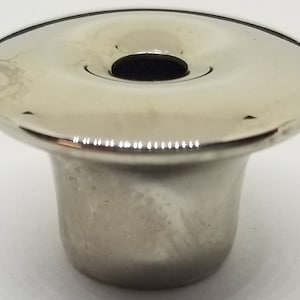 May include: A silver metal candle holder with a wide, flat top and a narrow base.