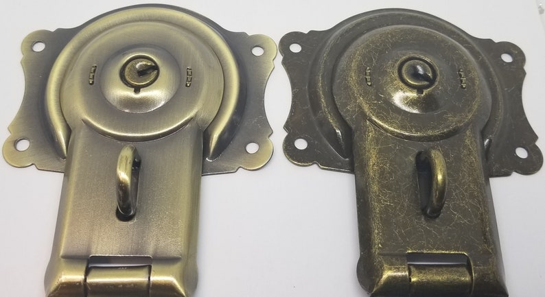 May include: Two antique-style brass cabinet door latches with a keyhole and a hook. The latches have a distressed finish.