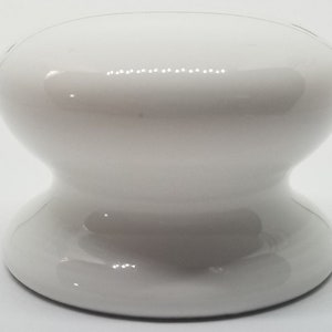 May include: White ceramic knob with a rounded top and a wider base. The knob is smooth and glossy.