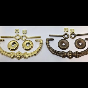 May include: Two sets of ornate brass drawer pulls, one set in polished brass and the other in an antique brass finish. Each set includes two pulls, two mounting plates, and two screws.