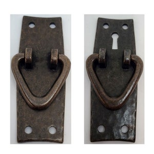 May include: Two antique bronze cabinet pulls with a heart-shaped design. Each pull has two holes for mounting and a keyhole on the right side.