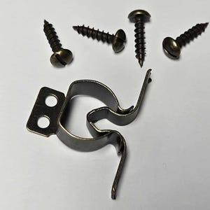 May include: A metal cabinet door catch with two screws. The catch is black and has a curved shape. The screws are also black and have a round head.