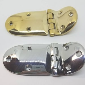 May include: Two metal hinges, one in polished brass and one in polished chrome. Both hinges are designed for use on a door or lid and have a rounded shape.