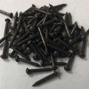 K&ouml;nnte beinhalten: Ein Haufen dunkelbrauner Rei&szlig;n&auml;gel mit abgerundeten K&ouml;pfen. Die Rei&szlig;n&auml;gel sind aus Metall und etwa 2,5 cm lang.