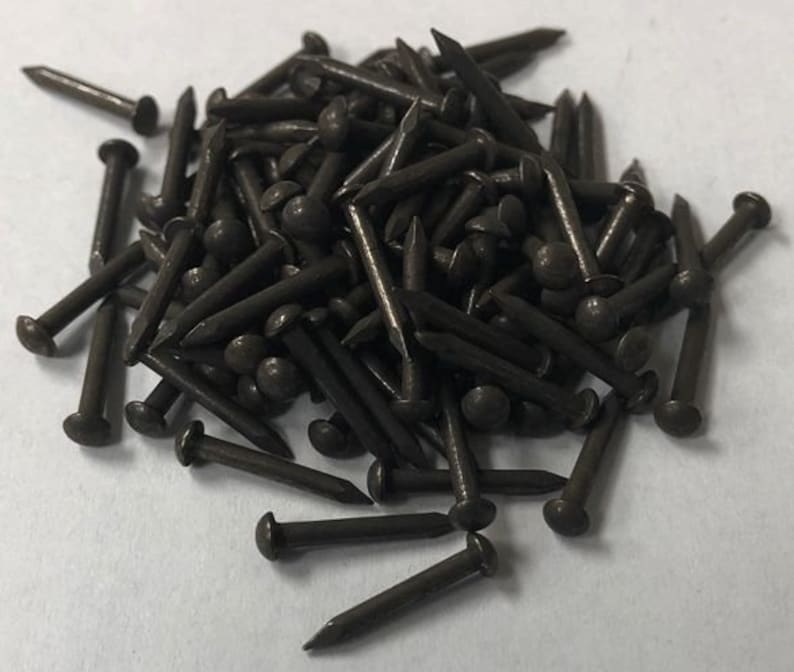 K&ouml;nnte beinhalten: Ein Haufen dunkelbrauner Rei&szlig;n&auml;gel mit abgerundeten K&ouml;pfen. Die Rei&szlig;n&auml;gel sind aus Metall und etwa 2,5 cm lang.