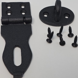 May include: Black cast iron gate latch set. The set includes a hinged latch, a strike plate with an eye, and several screws. The latch and strike plate have a textured finish and are designed for durability. Ideal for gates and doors.
