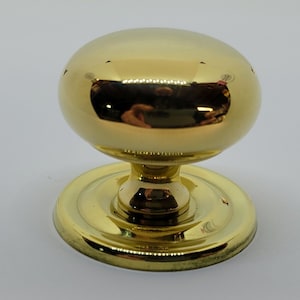 May include: A shiny, gold-colored door knob with a rounded top and a circular base. The knob has a reflective surface, and the base is slightly wider than the stem. This hardware is suitable for interior doors.