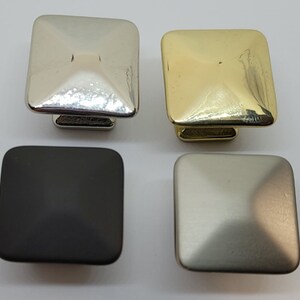 May include: Four square cabinet knobs in different finishes: polished nickel, brushed nickel, black, and brass.