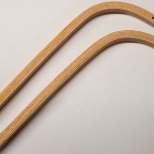 May include: Two unfinished wooden chair arms with a slight curve and a hole drilled at the end of each arm.