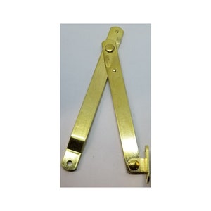 May include: A gold-toned metal hinge with two arms that fold together. The hinge has a rounded end and a flat end.