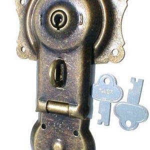 May include: Antique brass lock with a keyhole and two keys. The lock has a round shape and a hinged lid. The keys are silver and have a cloud-like shape.