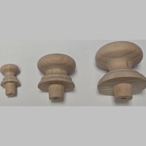 May include: Three unfinished light brown wooden knobs of varying sizes arranged in a row. Each knob features a smooth, rounded top, a central decorative collar, and a cylindrical base with a small hole at the bottom for mounting purposes.