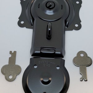 May include: Black metal latch with a keyhole and a small metal loop. The latch is in two pieces, one with a round base and the other with a rectangular base. Two silver keys are included.
