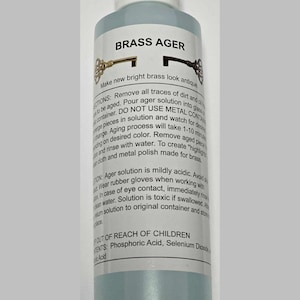May include: A clear glass bottle with a white cap labeled "Brass Ager" and instructions on how to use the solution to make brass look antique. The bottle is sitting on a white background.