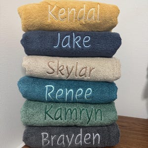 May include: A stack of six towels with different colors and embroidered names: Kendal, Jake, Skylar, Renee, Kamryn, and Brayden.