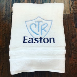 May include: White bath towel with blue and light blue embroidered shield with the letters CTR and the name Easton below.