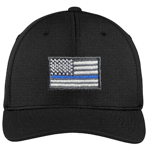 May include: Black baseball cap with an embroidered American flag with a blue line across the middle.