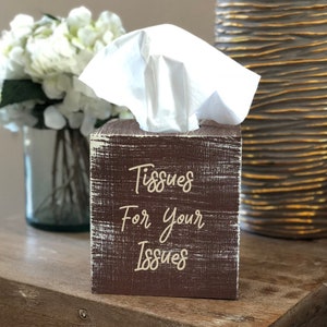 May include: A brown wooden tissue box with white distressed paint. The box has the text "Tissues For Your Issues" written in white cursive font.