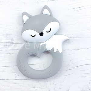 May include: Gray silicone baby teether shaped like a fox with a white tail. The teether has a ring in the middle for easy gripping.