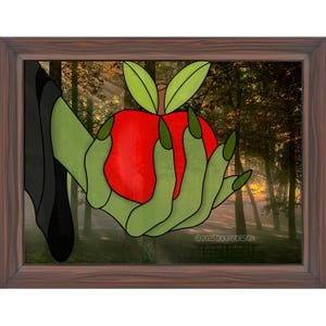 May include: A framed stained glass art piece depicting a green hand with long pointed fingers holding a bright red apple with two green leaves. The background shows a forest scene with trees and sunlight. The text 2025DOOR9DESIGN is visible.
