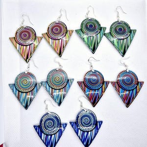 May include: A set of six pairs of colourful geometric earrings. Each earring features a round, multi-coloured, spiral design with a smaller triangle shape underneath. The earrings are made of wood and have silver hooks.