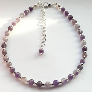 May include: A delicate anklet made with small, round amethyst beads and silver spacer beads. The anklet has an adjustable silver chain.