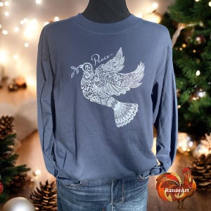 May include: A long-sleeved, navy blue t-shirt with a white, intricate design of a dove with an olive branch in its beak. The word "Peace" is written above the dove.