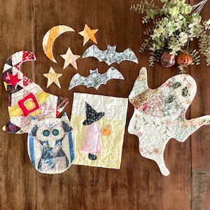 May include: A collection of quilted fabric Halloween decorations including a witch hat, a ghost, an owl, a rectangular panel with a witch, two bats, a crescent moon, and three stars, all featuring various colorful patterned textiles and stitching.