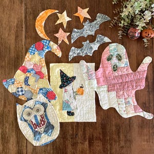 May include: A collection of quilted fabric Halloween decorations including a patchwork witch hat, a ghost, an owl, and a rectangular panel featuring a witch. Additional fabric cutouts include a crescent moon, two stars, and two bats.
