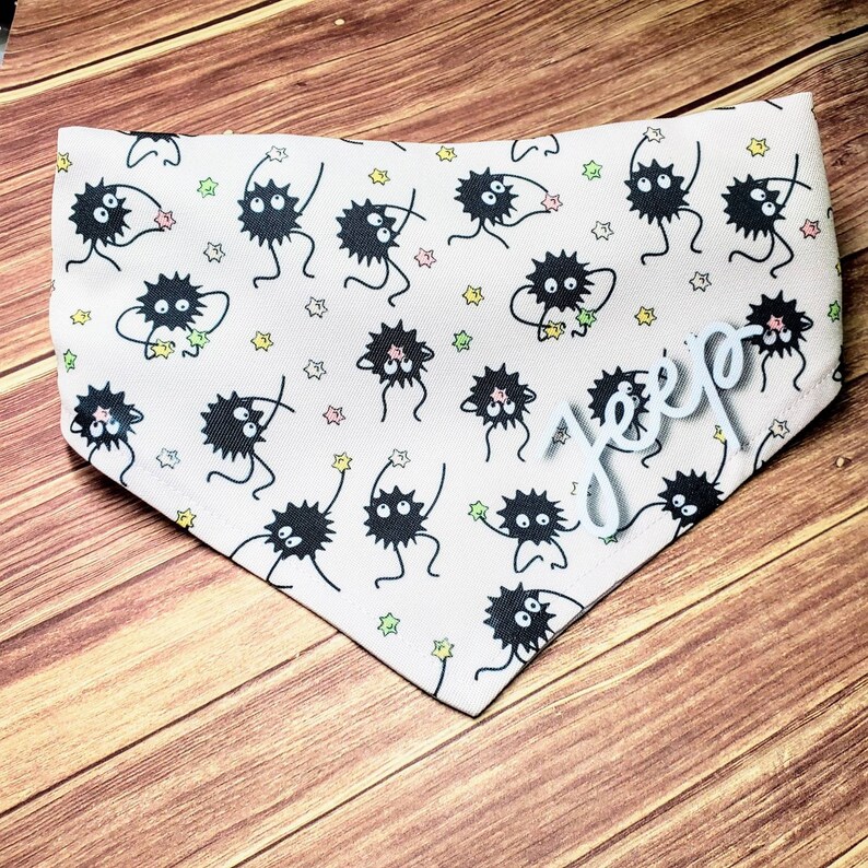 May include: A pink bandana with a white background and a repeating pattern of black, cartoon-like creatures with stars. The bandana has the word "Jeep" written in white on the bottom right corner.