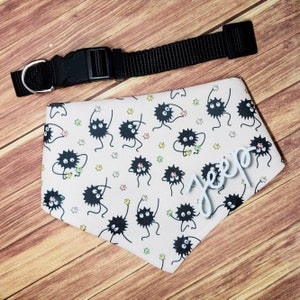 May include: A pink dog bandana with a black and white print of cartoon characters. The bandana has a white name tag that says "Jepp" on it.