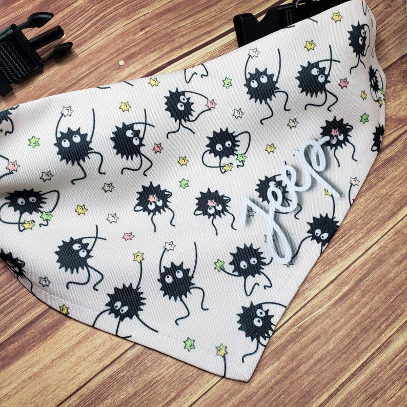 May include: A white bandana with a black and white print of cartoon creatures with stars. The bandana has the name "Jeep" written in white on it.