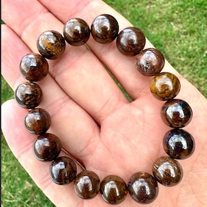 May include: A brown and gold gemstone bracelet with round beads. The bracelet is made of natural stones and has a polished finish.