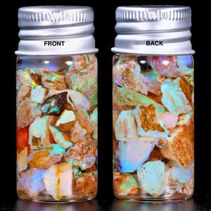 May include: Two small glass jars filled with colourful opal fragments. The jars have silver lids and are labelled "FRONT" and "BACK". The opals display a variety of colours, including white, brown, orange, and blue, with iridescent flashes.