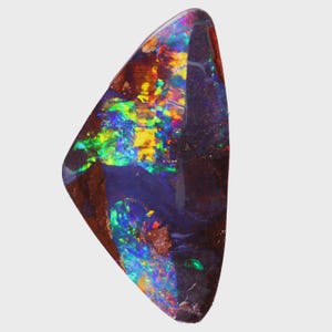 May include: A triangular-shaped boulder opal gemstone featuring a dark brown ironstone matrix with vibrant flashes of iridescent green, yellow, orange, and blue colours across its polished surface, displaying a natural play of colour pattern.